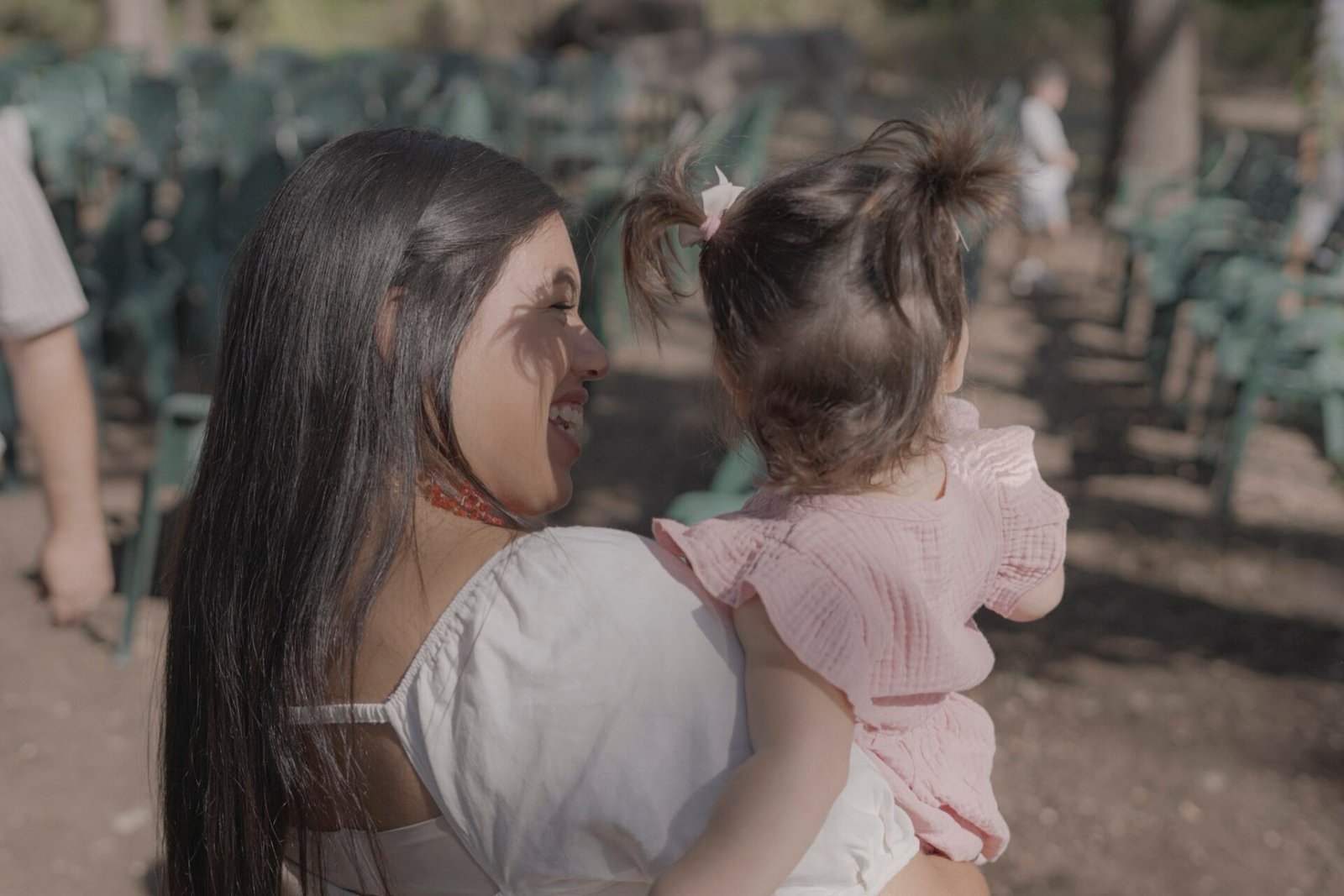 Une invitée sourit à une petite fille dans ses bras pendant la fête.
