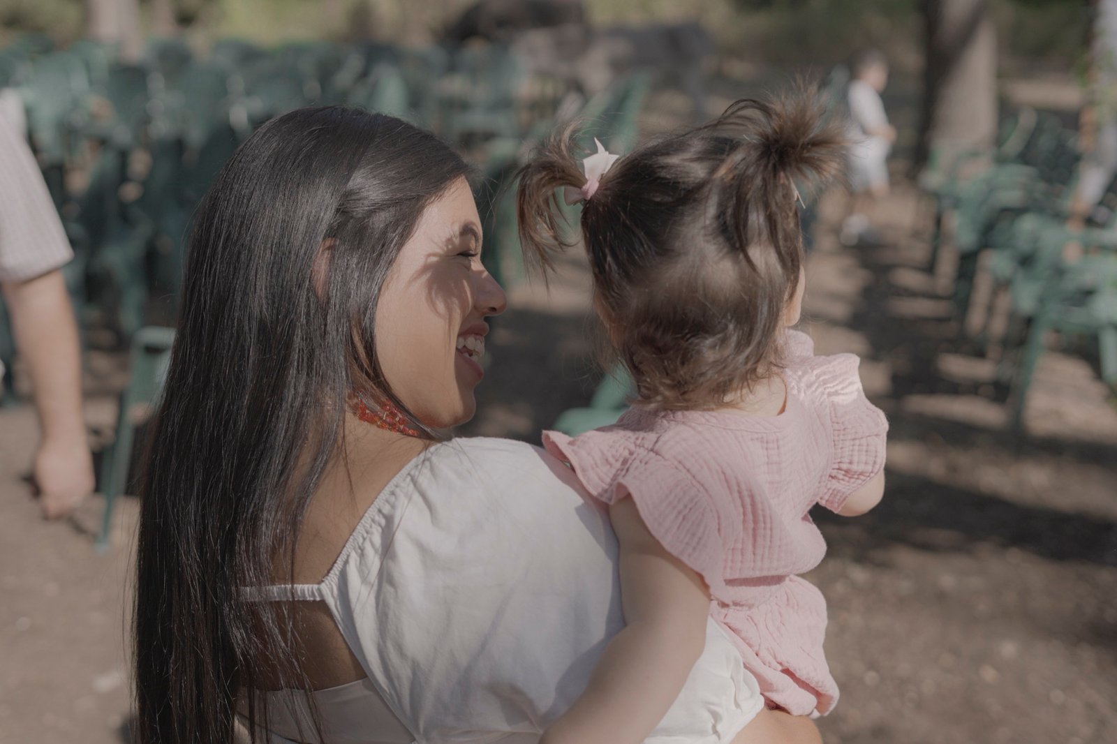 Une invitée sourit à une petite fille dans ses bras pendant la fête.