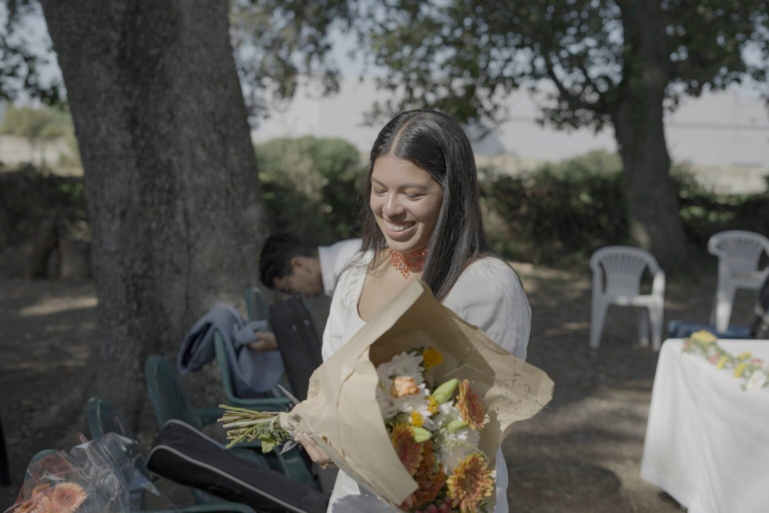 Une femme souriante recevant un bouquet de fleurs en extérieur