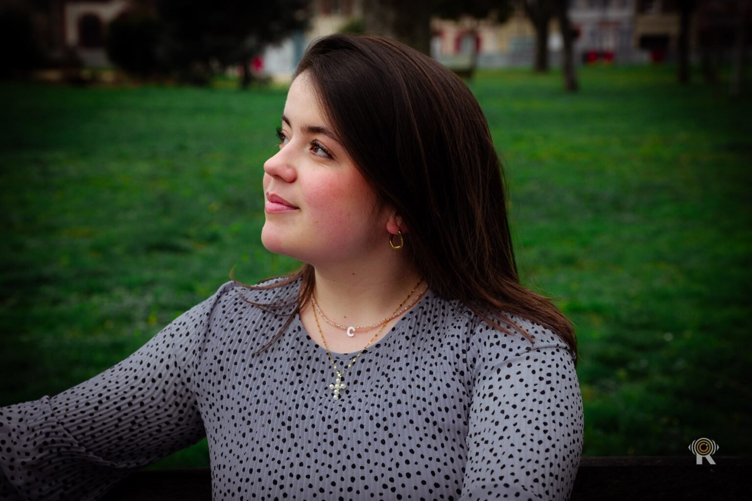 Portrait en extérieur d'une jeune femme en chemisier à pois, le regard levé