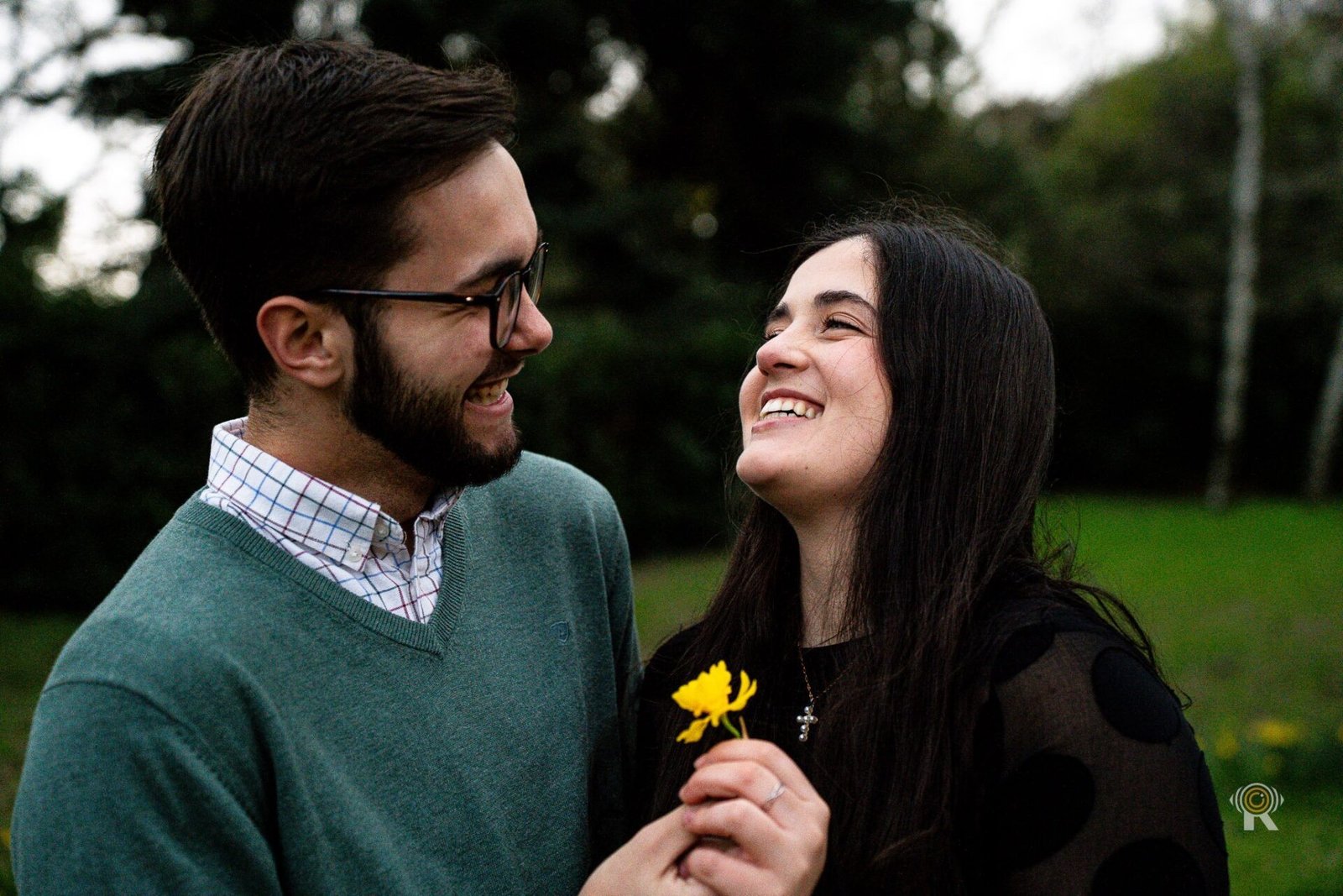Un couple rit ensemble pendant une séance photo au parc.