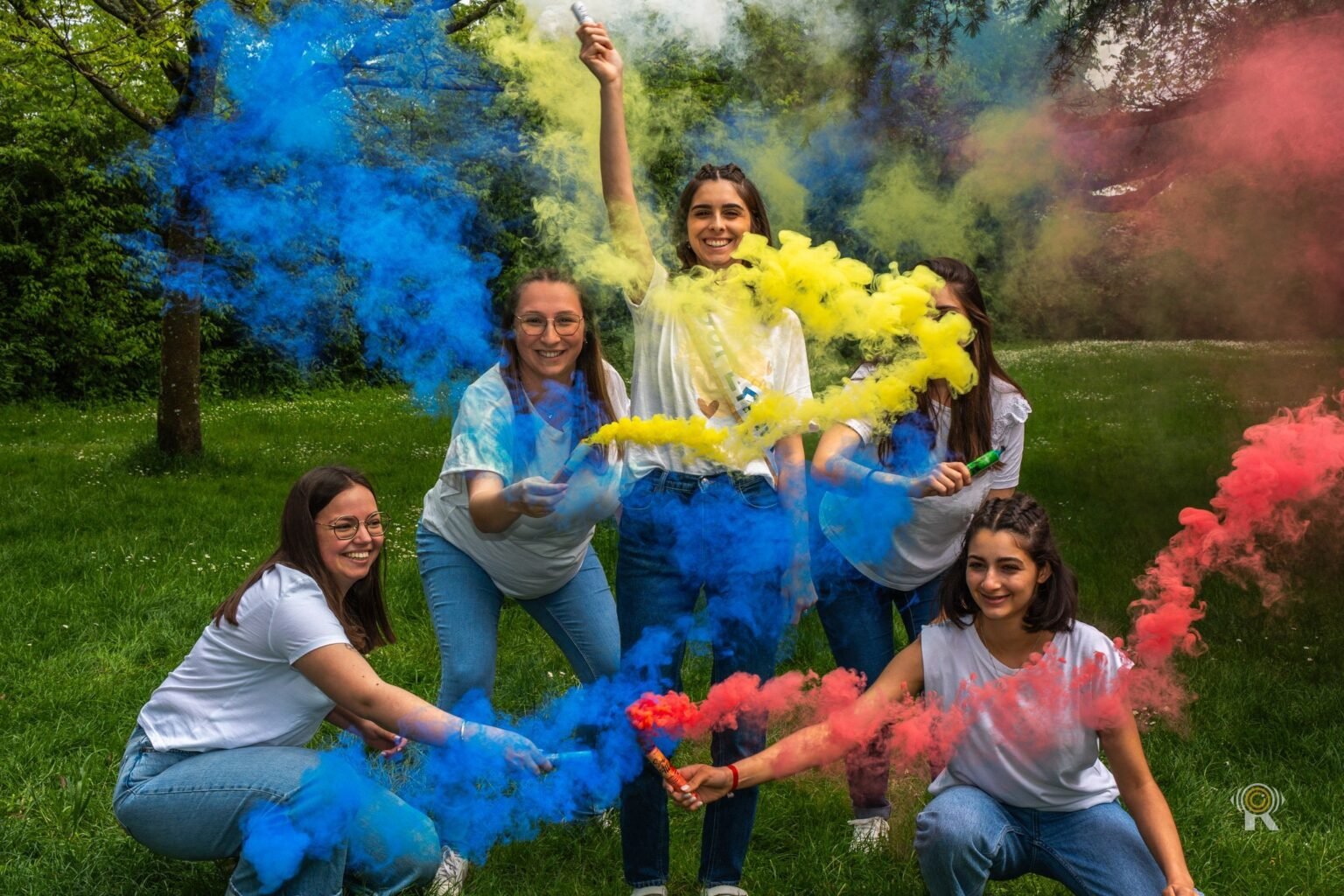 Un groupe de femmes lançant de la poudre colorée bleue, rose et jaune