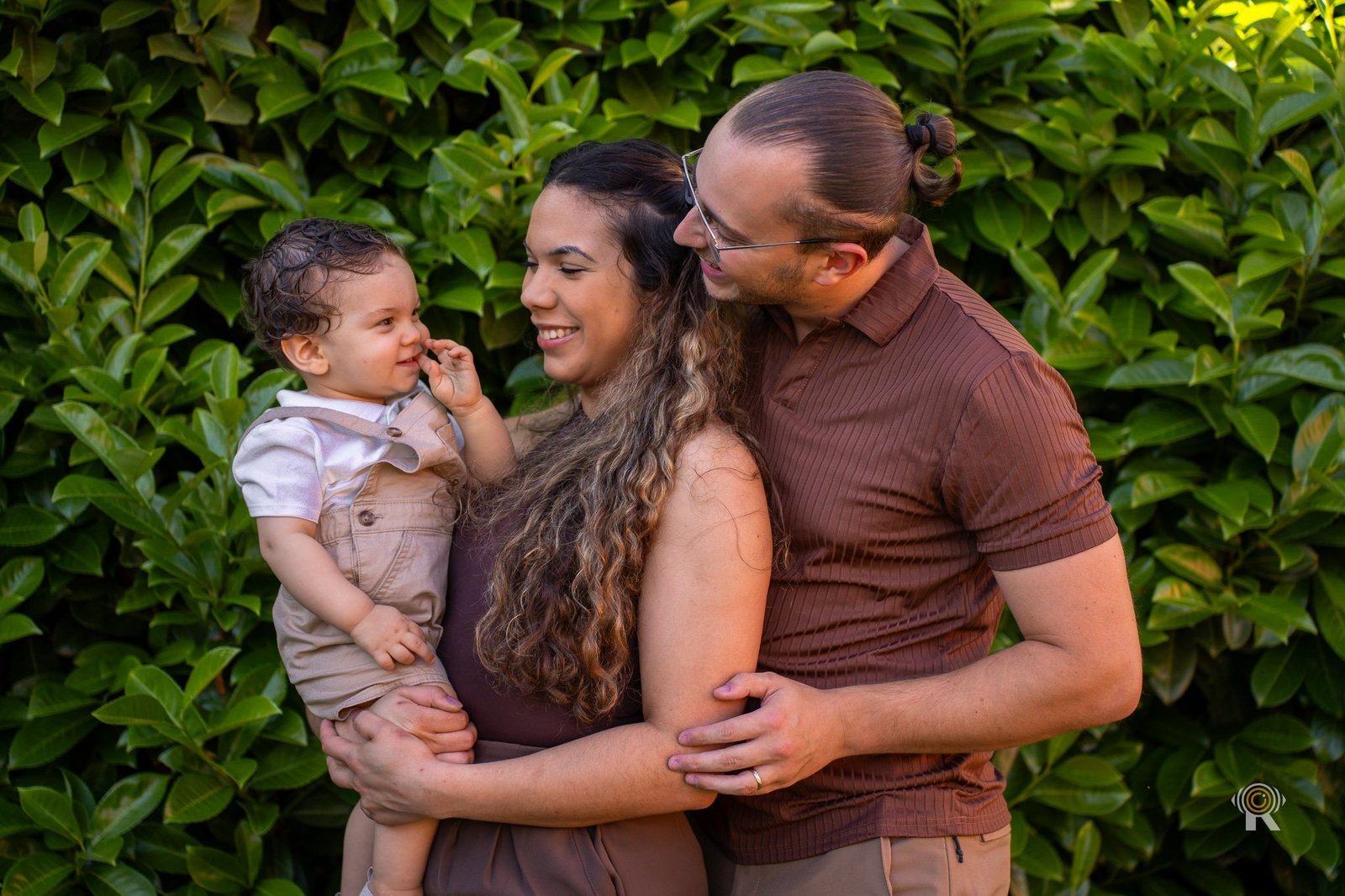 Famille avec bébé d'un an enlacée en extérieur, suivi famille photo et vidéo, Rufino Studio Toulouse.