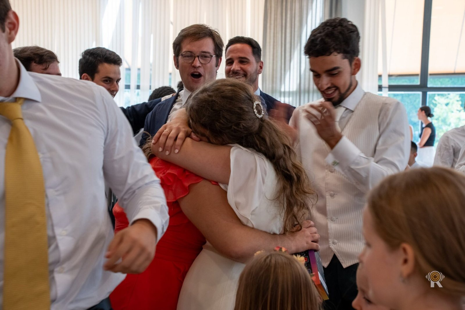 Les proches de la mariée la serrent dans leurs bras en riant.