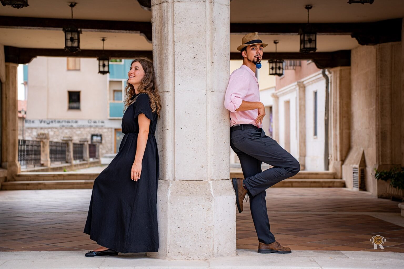 Une mariée en robe noire, debout près d'une colonne en pierre.