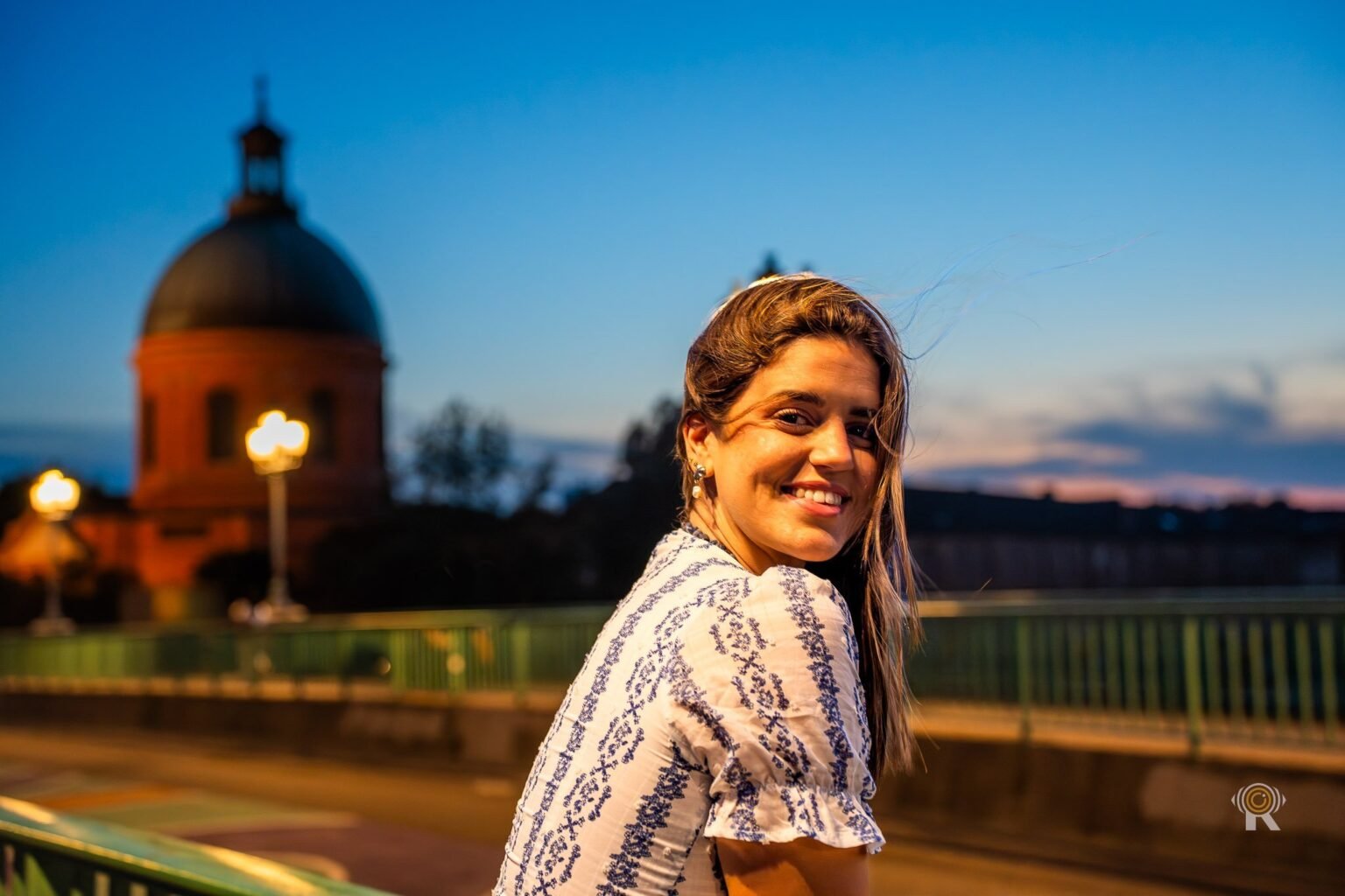 Portrait sur le pont Saint-Pierre à Toulouse, le dôme de la Grave éclairé à l'arrière-plan