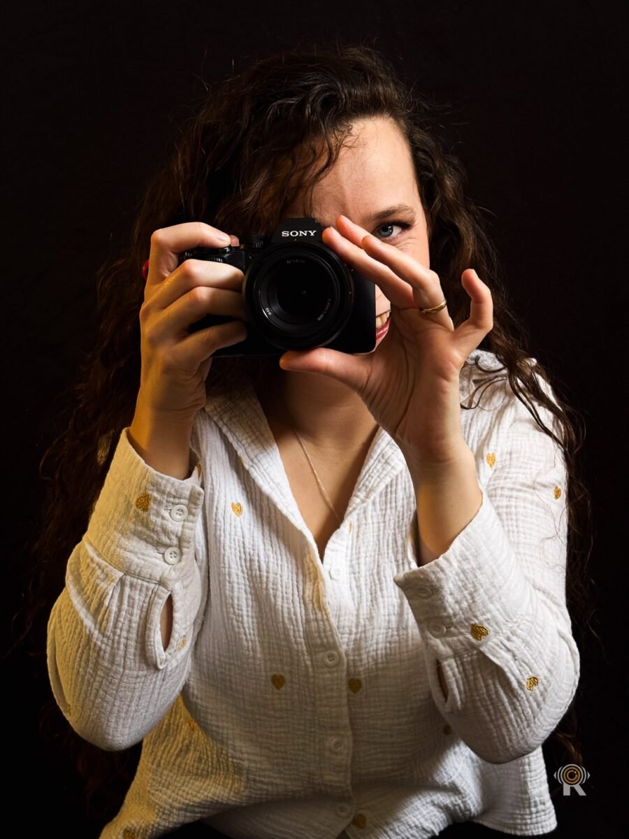 Jennifer Igreja derrière un boîtier Sony, un œil bleu ouvert au-dessus du boîtier, plan serré