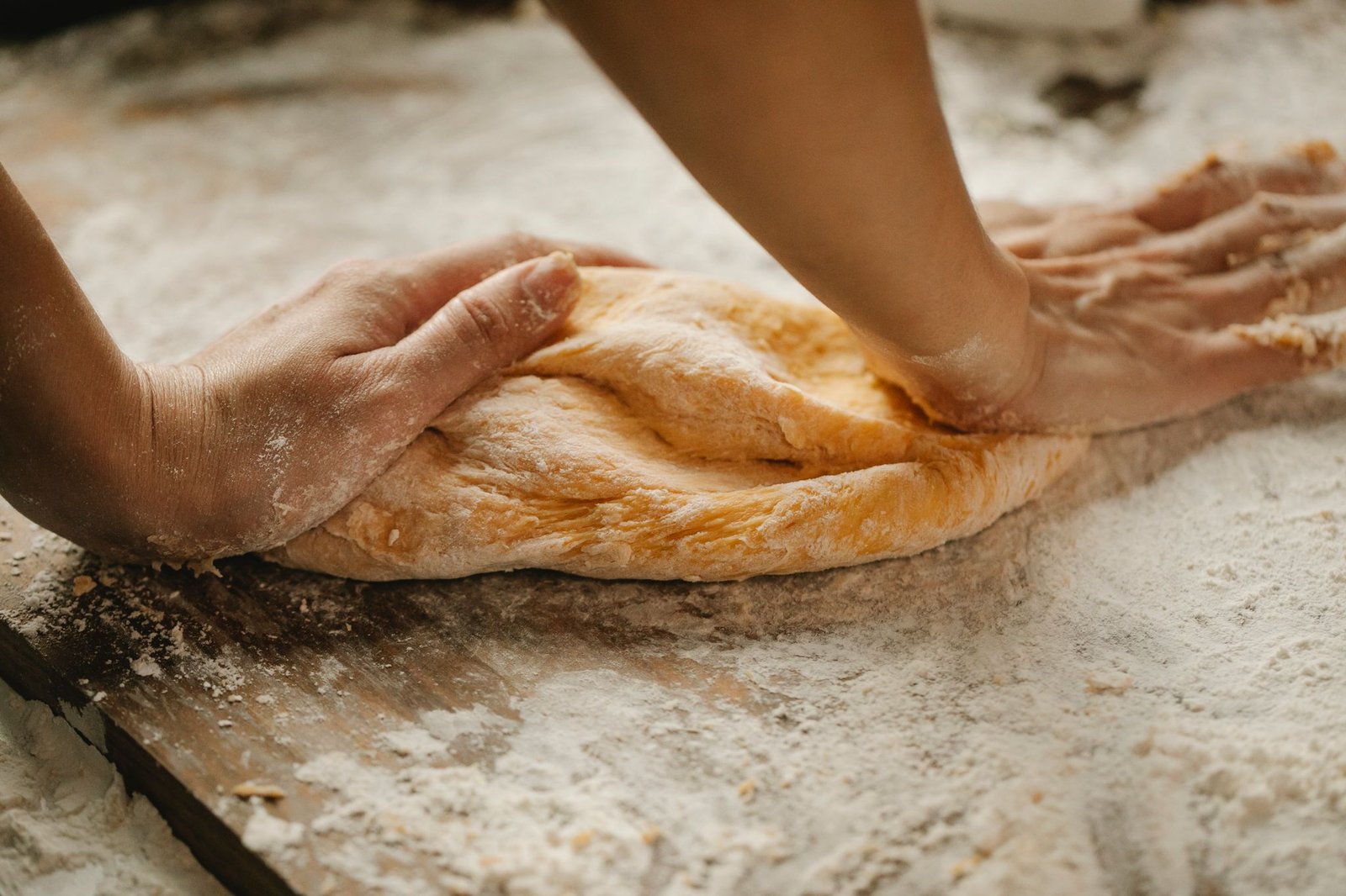 Mains d'un boulanger pétrissant la pâte sur un plan fariné, reportage de métier Dans les Coulisses, Rufino Studio photographe et vidéaste Toulouse.