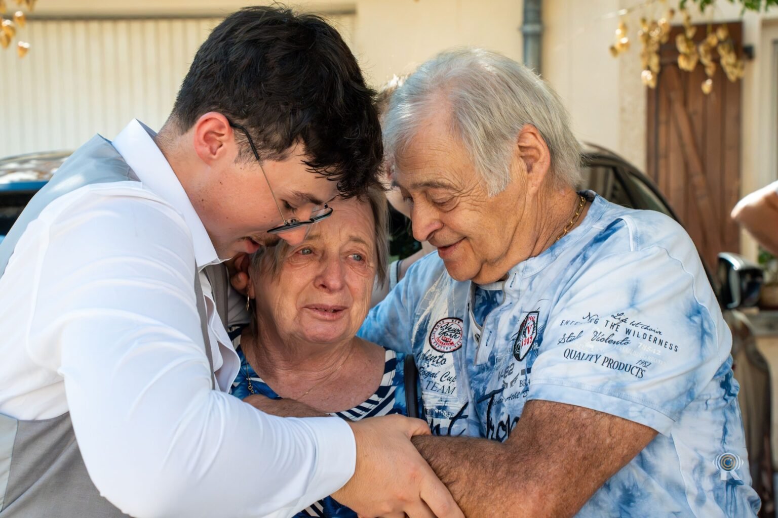 Le marié qui enlace ses grands-parents, émus.