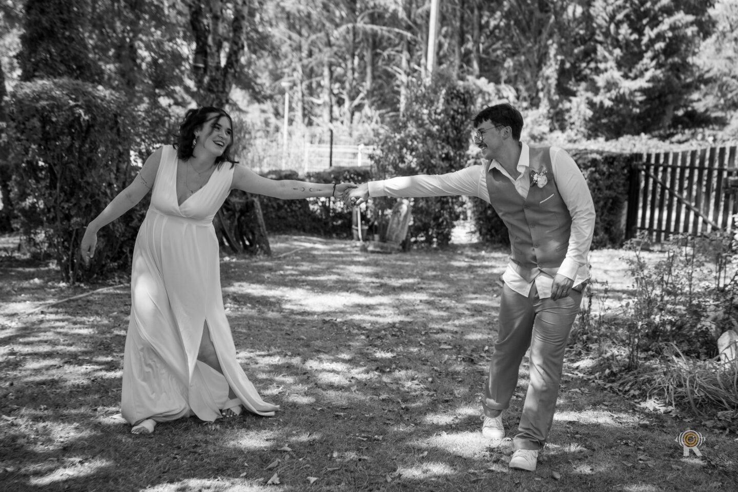 En noir et blanc, Jessica et Nathan dansent dans un jardin, main dans la main. Rufino Studio.