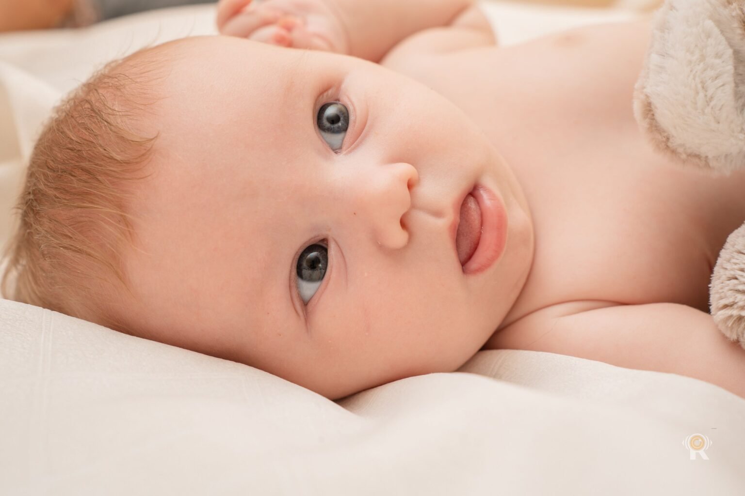 Un bébé allongé près de son doudou, à la lumière douce