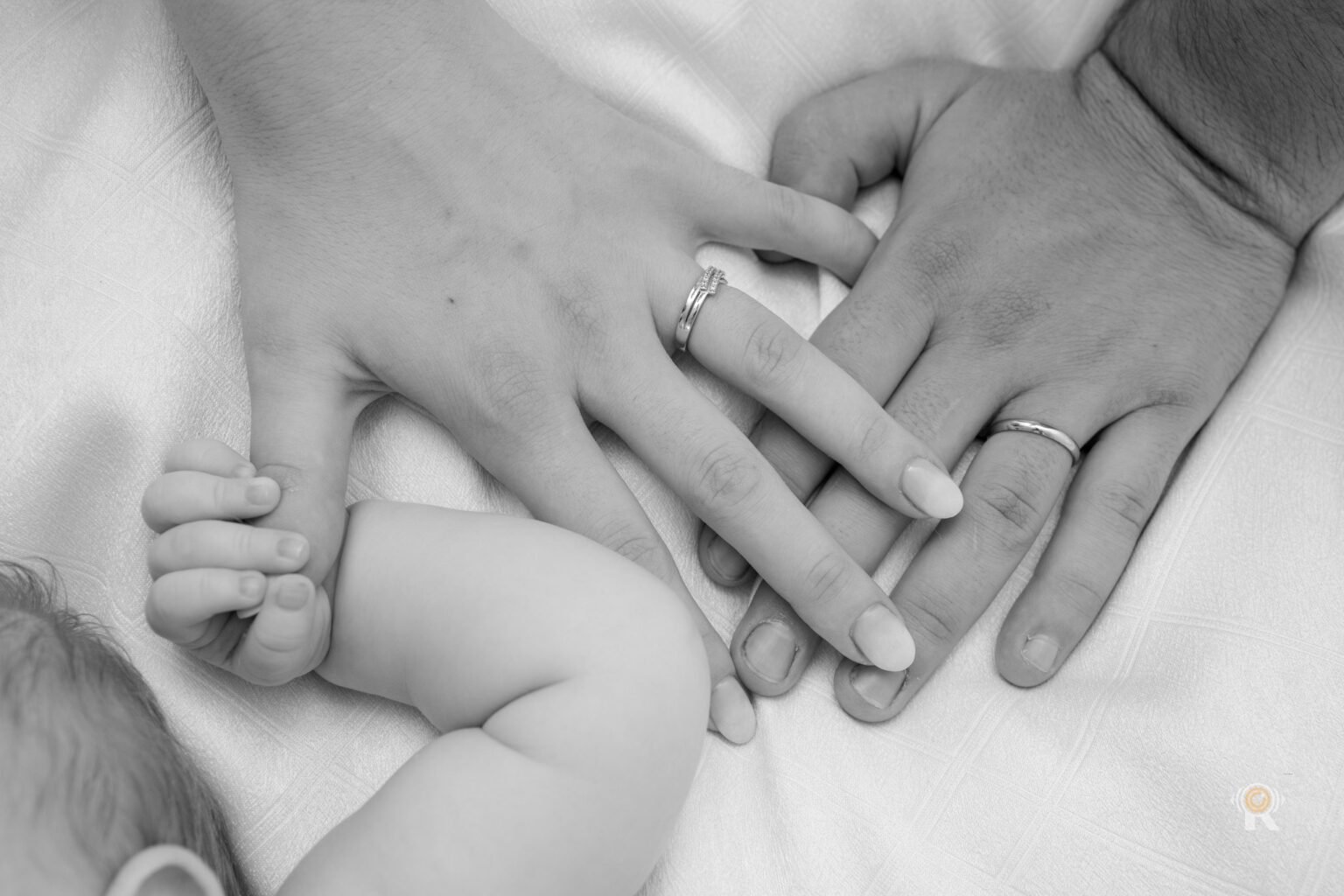 En noir et blanc, les mains des parents autour de la main du bébé