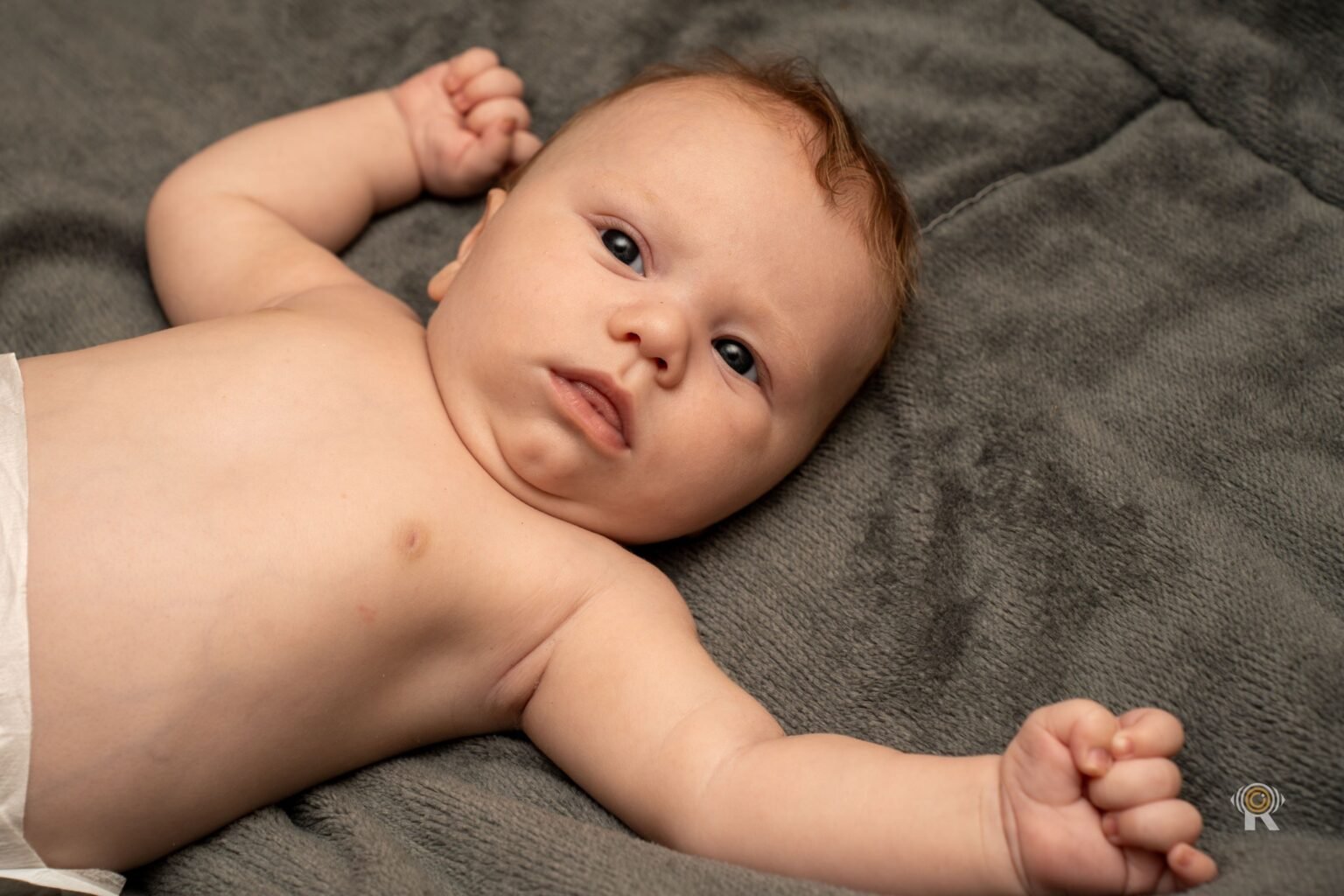 Un bébé éveillé sur une couverture, le regard vers l'objectif