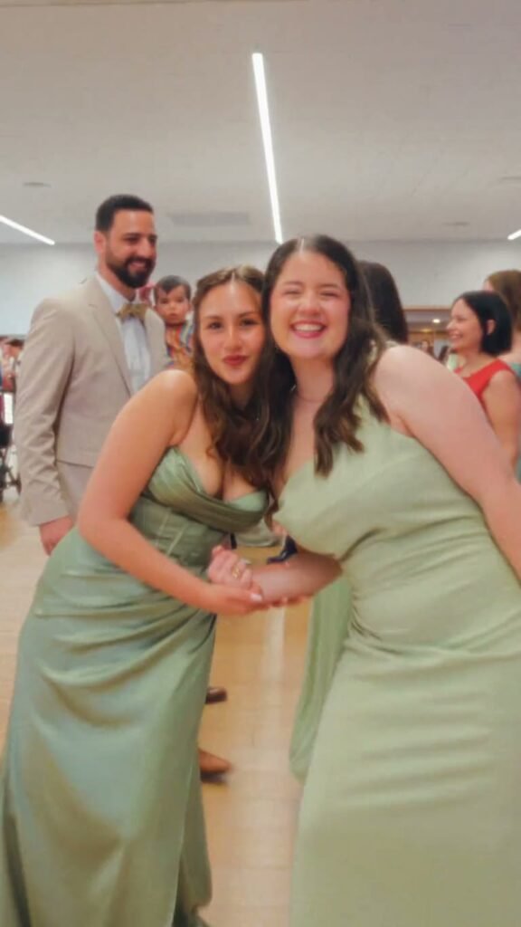 Deux invitées en robe vert d’eau se tiennent par la taille et sourient, pendant la soirée.