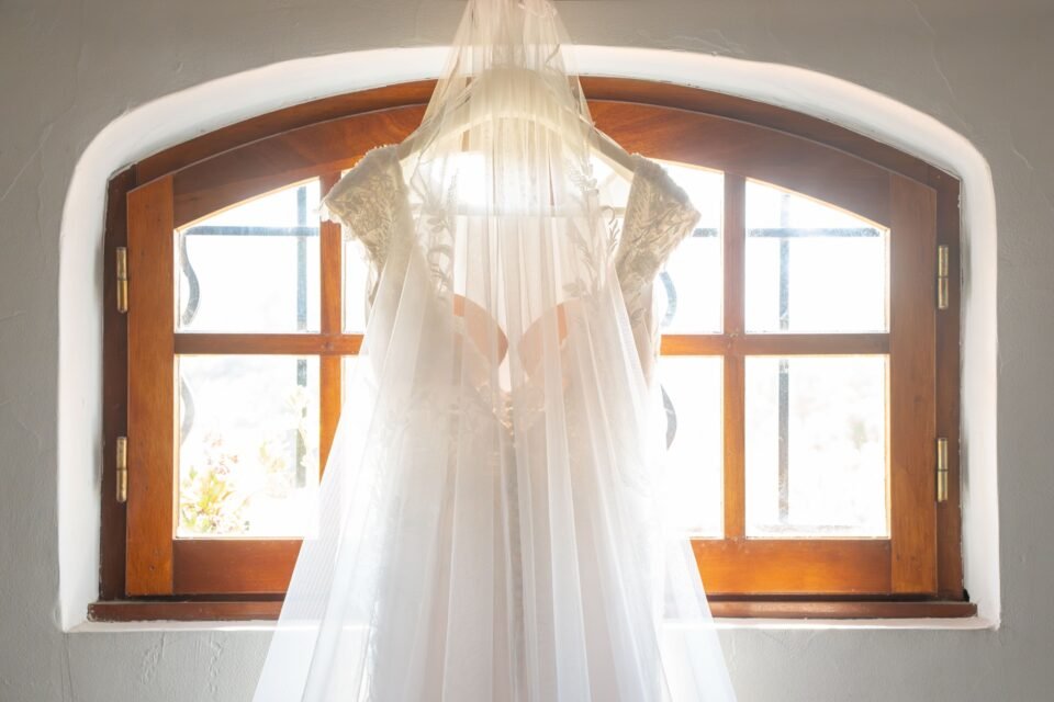 Robe et voile à contre-jour devant une fenêtre en arc.