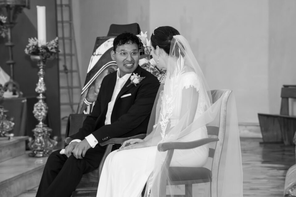 En noir et blanc, assis côte à côte, ils se regardent et sourient.