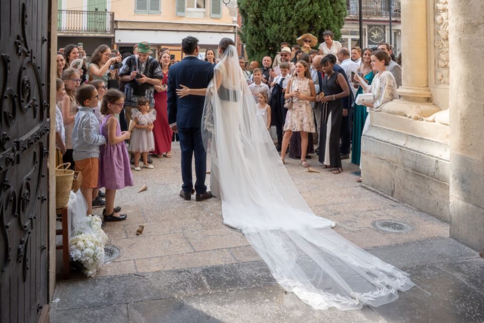 À la porte de l’église, des invités attendent, le voile posé à terre.